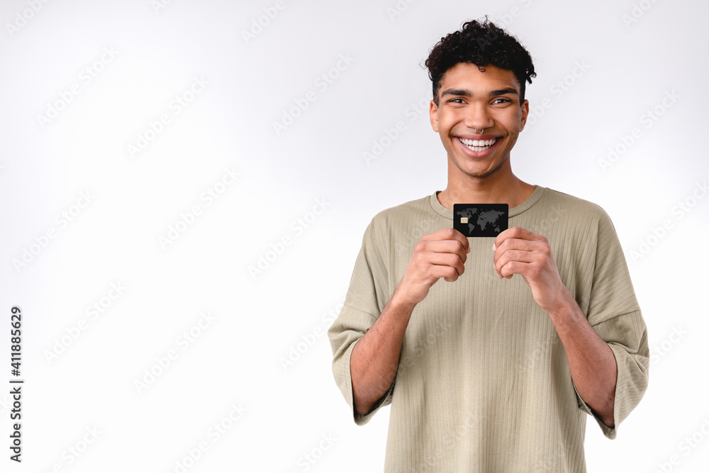 Cheerful young handsome african boy showing credit card in casual outfit isolated over white background Cheerful young handsome african boy showing credit card in casual outfit isolated over white background