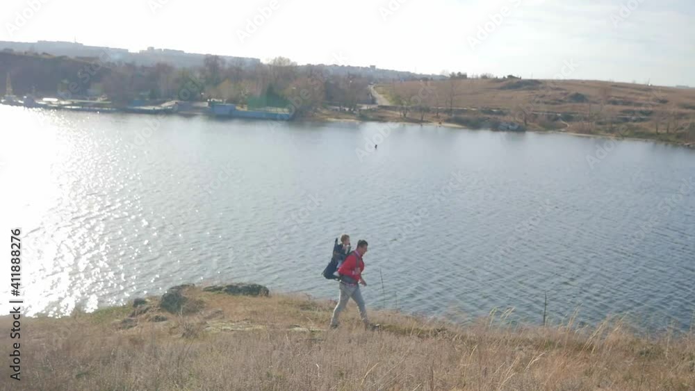 Father with little son in touristic backpack looking at beautiful view in the mountains Father with little son in touristic backpack looking at beautiful view in the mountains