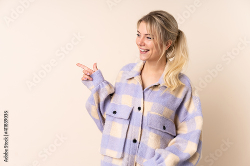 Blonde woman over isolated background pointing finger to the side and presenting a product