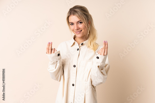 Blonde woman over isolated background making money gesture