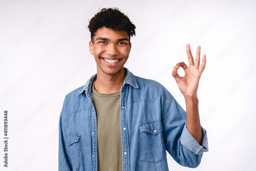 Positive young mixed-race man showing okay gesture isolated over white background Positive young mixed-race man showing okay gesture isolated over white background