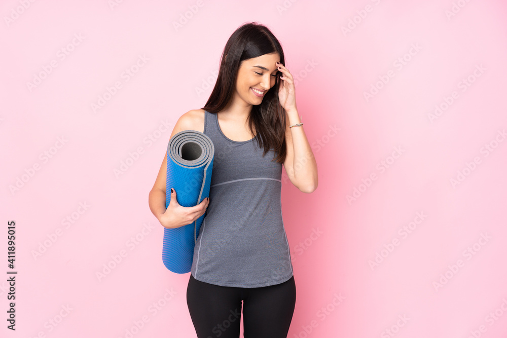 Fototapeta premium Young caucasian woman with mat isolated on pink background laughing