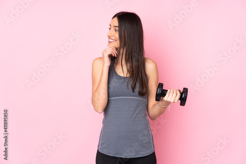 Young woman making weightlifting isolated on pink background thinking an idea and looking side © luismolinero