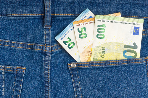 euro banknotes in blue jeans back pocket.