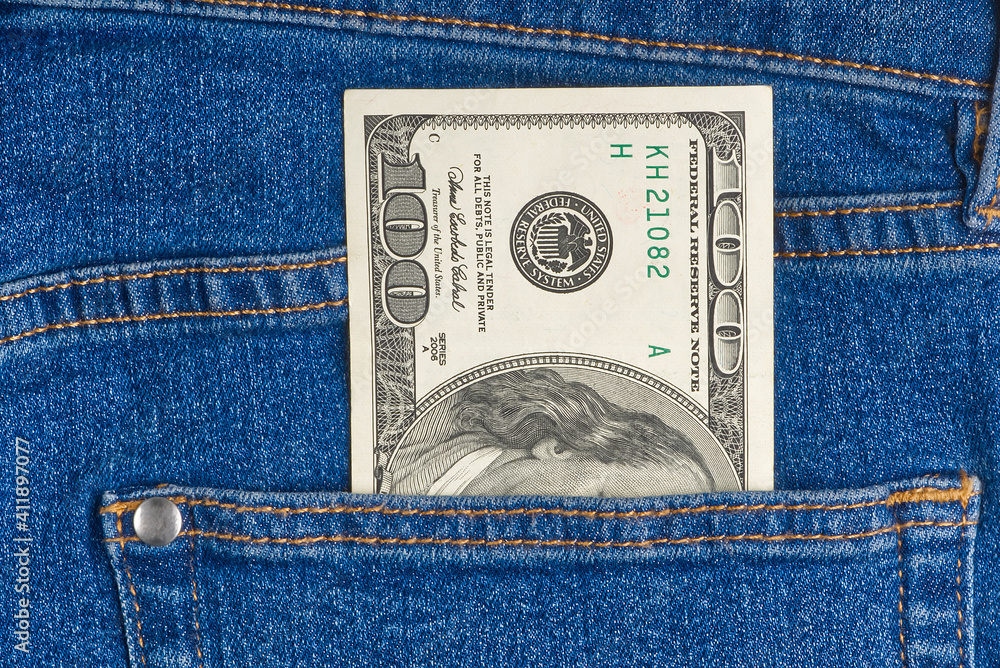 one hundred dollar note in the back pocket of blue jeans. dollar bills in jeans pocket one hundred dollar note in the back pocket of blue jeans. dollar bills in jeans pocket