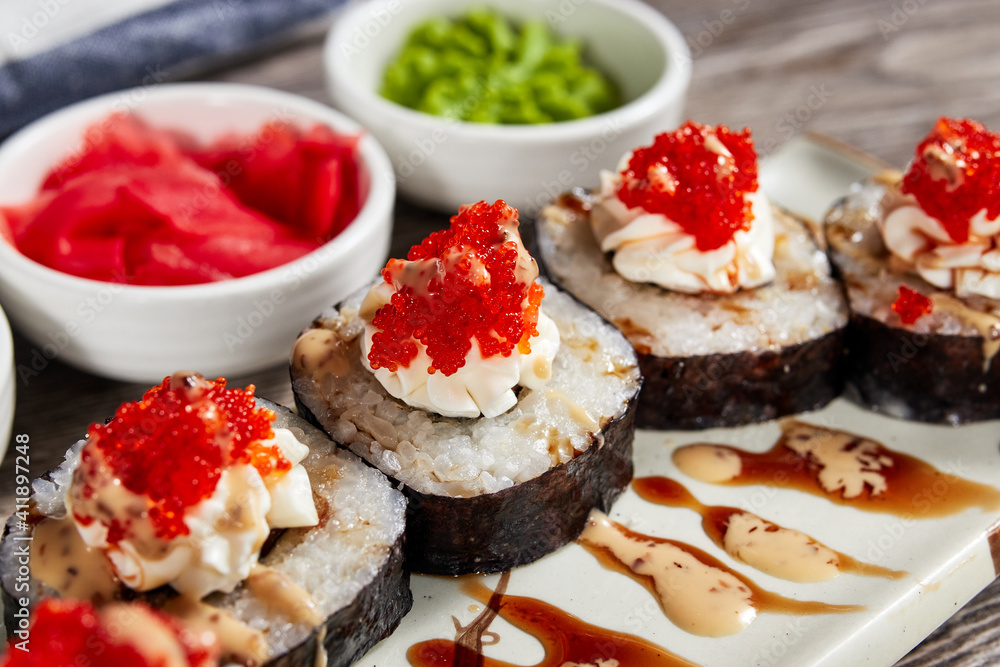 japanese sushi rolls in a rectangular plate on a light wooden table japanese sushi rolls in a rectangular plate on a light wooden table