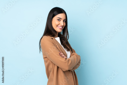 Young caucasian woman isolated on blue background with arms crossed and looking forward photo