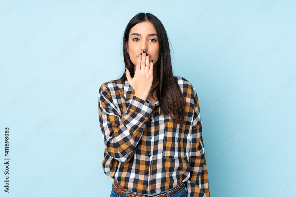 Young caucasian woman isolated on blue background covering mouth with hand Young caucasian woman isolated on blue background covering mouth with hand