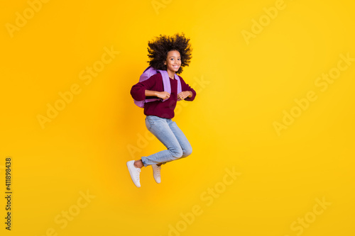 Full length profile portrait of dark skin girl jump carry bag wear pullover isolated on yellow color background