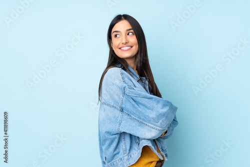 Foto Young caucasian woman isolated on blue background looking to the side and smilin