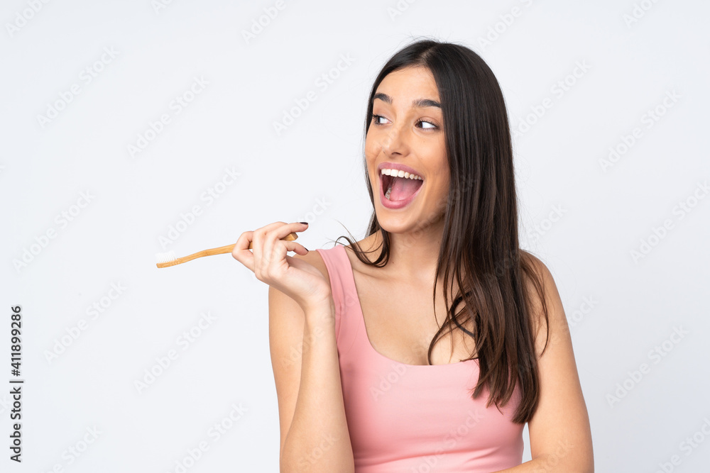 Young caucasian woman isolated on white background with a toothbrush and surprised expression