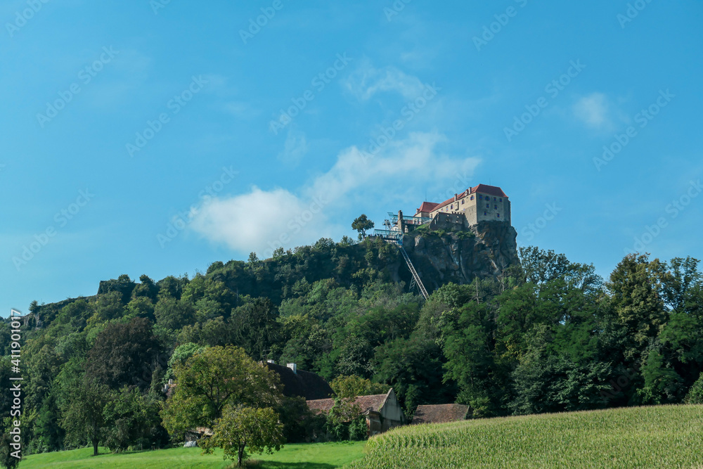 A distant view on the Riegersburg castle in Austria towering above the area. Clear blue sky above the castle. The massive fortress was build on the rock. Defensive structure from the middle ages. Calm