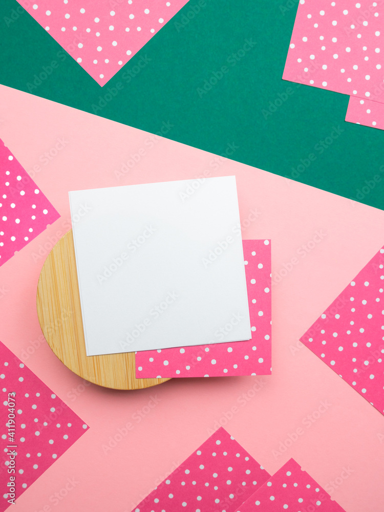 Abstract flatlay,close up top view square note sheets on round wooden base,dark green diagonal paper background,corners of pink paper with white polka dots around perimeter.Design pattern copy space. Abstract flatlay,close up top view square note sheets on round wooden base,dark green diagonal paper background,corners of pink paper with white polka dots around perimeter.Design pattern copy space.