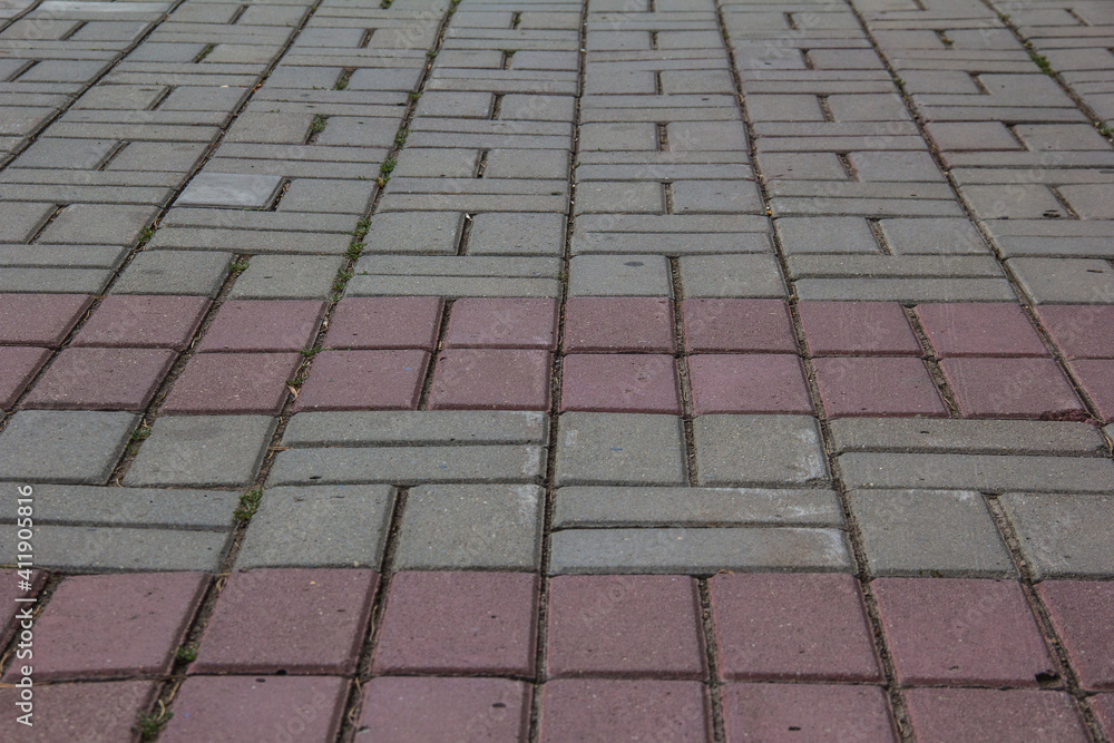 Fototapeta premium the sidewalk is paved with pink and gray tiles.