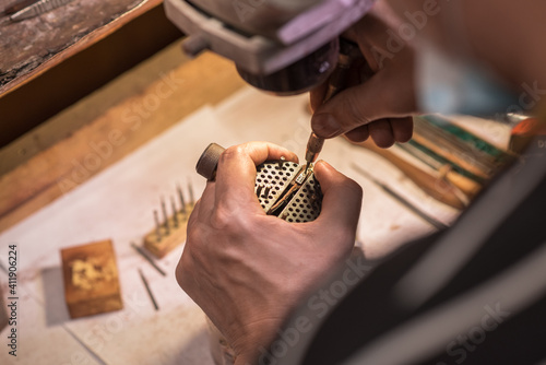 A male jeweler fixes a precious zirconium stone into a silver earring