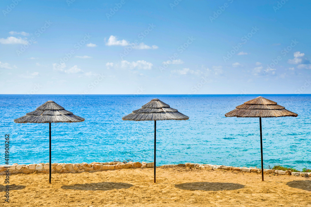three wooden umbrellas  on a sandy beach,beautiful viiew ,sunny day