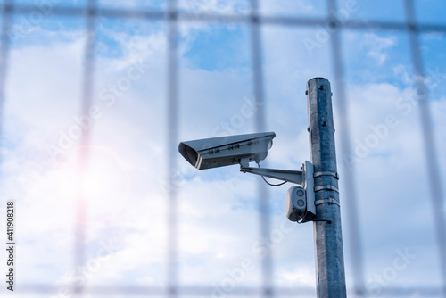 Tableau sur toile Street security camera next to iron fence, border, prison, concept picture