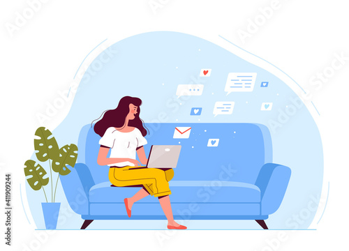 A young woman is sitting on the couch, holding a laptop and texting by email. The concept of remote work