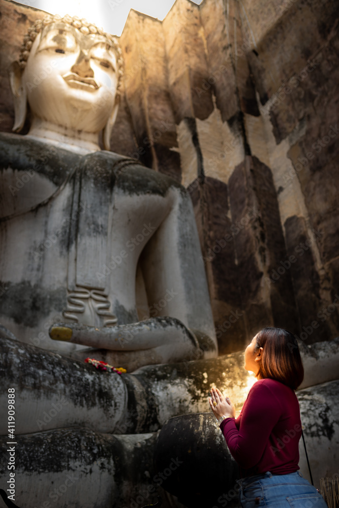 Asian woman to pay respect to Buddha statue at Wat Si Chum ,an ancient religious site of sukhothai , Thailand