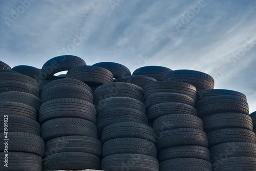 Pile of stacked old used car tires closeup on blue sky background