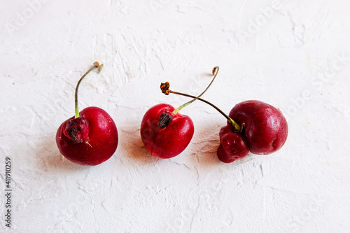 Trendy ugly organic fruits - three berries of sweet cherry on the table with copy space for text. Horizontal orientation. Buying imperfect products is a way to deal with food waste