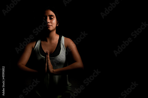 Hispanic woman doing yoga in the dark isolated
