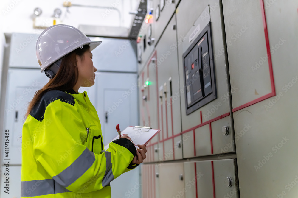 Asian electric engineer holding clipboard for checking and monitoring the electrical system in the control room,Technician thailand people working Asian electric engineer holding clipboard for checking and monitoring the electrical system in the control room,Technician thailand people working