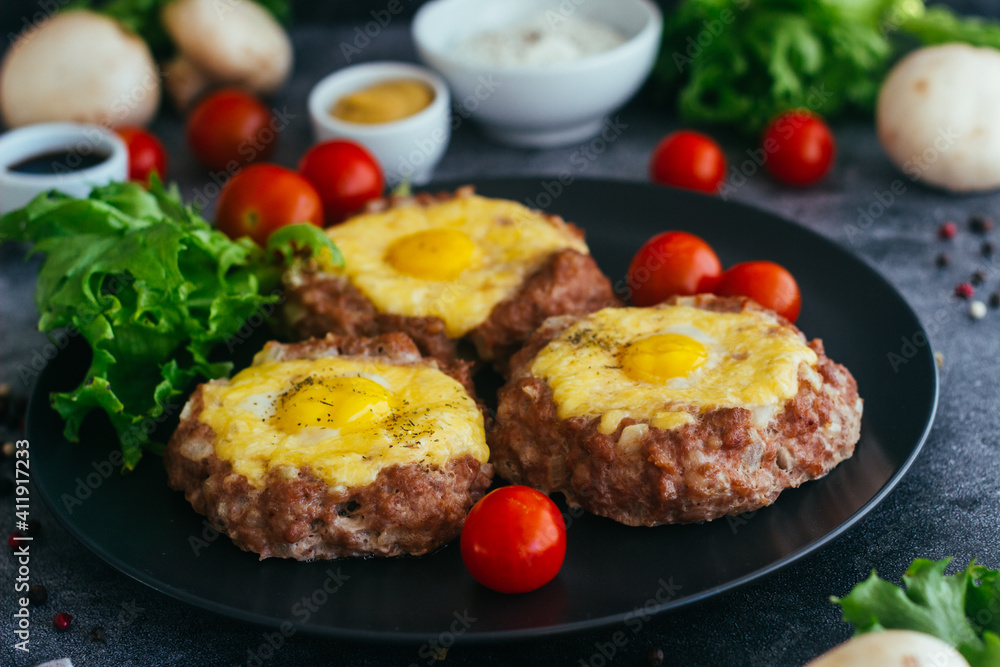Beefsteak with egg on a plate. Delicious hot dish. The dish is decorated with cherry tomatoes and herbs. Beefsteak on a plate Beefsteak with egg on a plate. Delicious hot dish. The dish is decorated with cherry tomatoes and herbs. Beefsteak on a plate