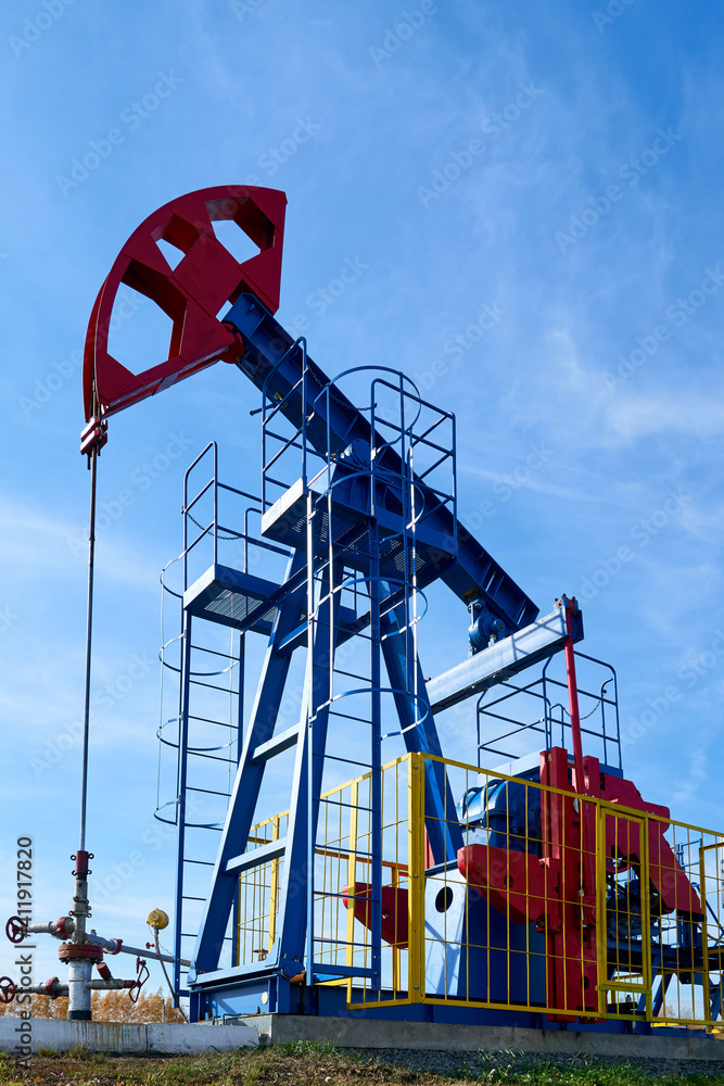 The blue and red oil rig on a sunny day against a blue sky. View from below. The blue and red oil rig on a sunny day against a blue sky. View from below.