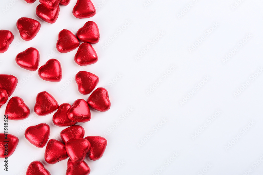 Heart shaped chocolate candies in red foil on white background, top view Heart shaped chocolate candies in red foil on white background, top view