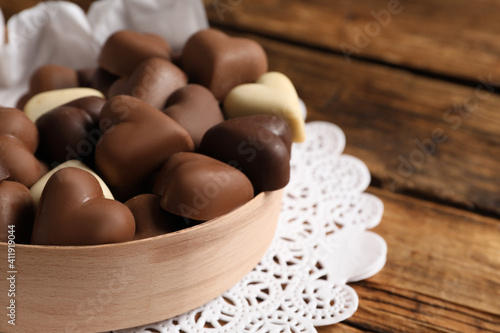 Delicious heart shaped chocolate candies on wooden table, closeup. Space for text
