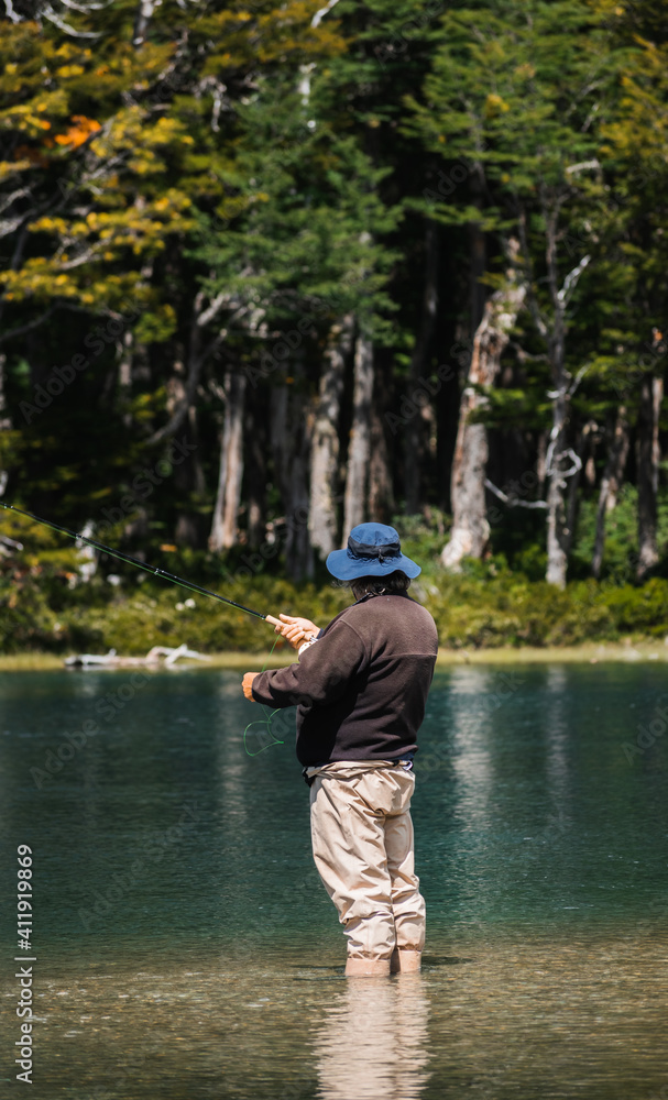 Fisherman immersed in the water of a lake with a fly rod in Argentina Fisherman immersed in the water of a lake with a fly rod in Argentina