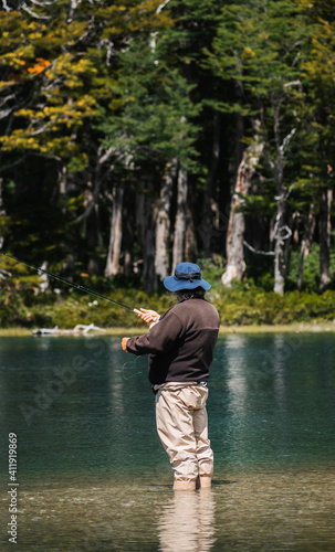 Fisherman immersed in the water of a lake with a fly rod in Argentina