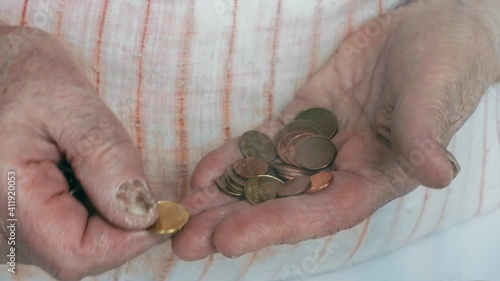 old woman counts pennies in her hands. pensioner counts coins. old woman's hands close-up