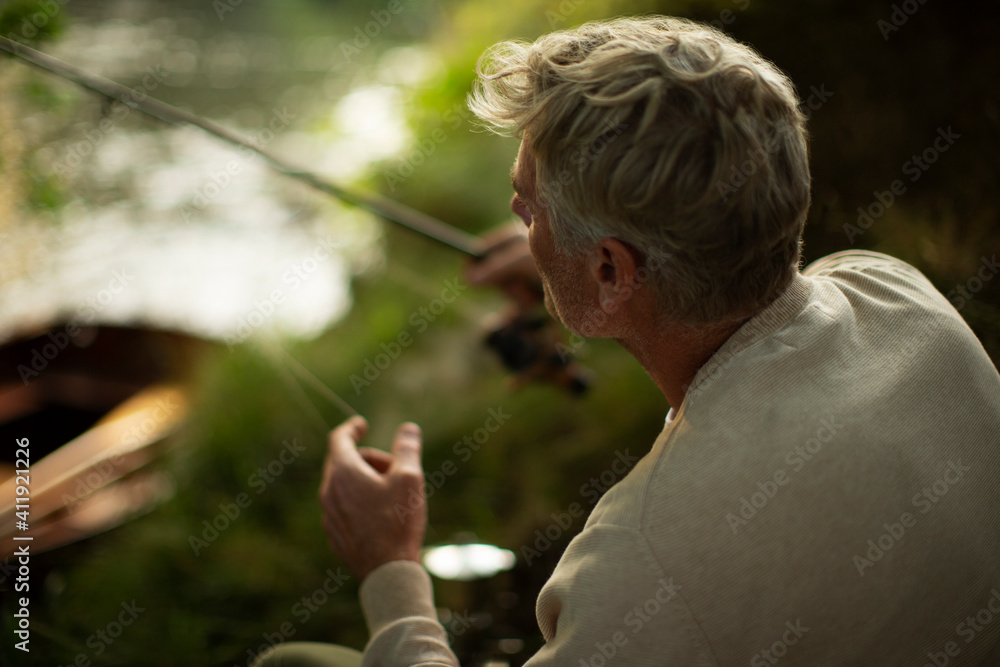 Man fly fishing at riverbank Man fly fishing at riverbank