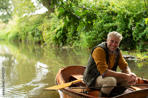 Portrait happy man fly fishing in boat on river photo