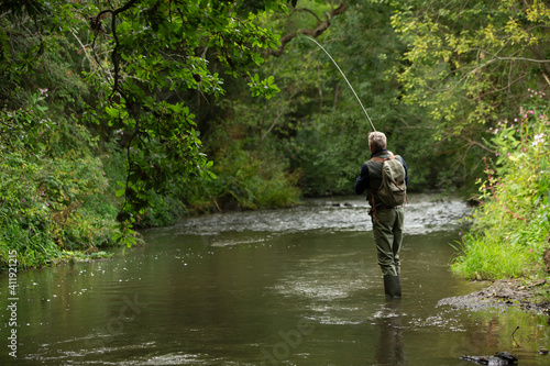 Man fly fishing at tranquil green river