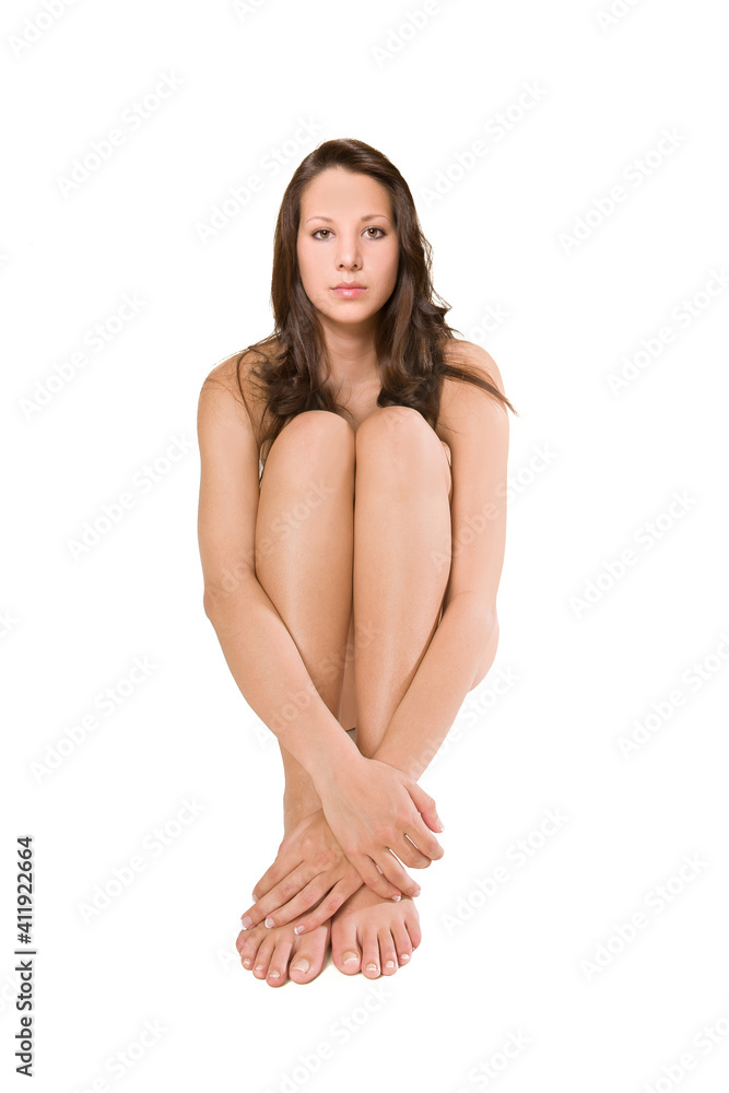 Beautiful brunette woman covering her body with her arms and legs, her private parts are not visible, isolated in front of white studio background Beautiful brunette woman covering her body with her arms and legs, her private parts are not visible, isolated in front of white studio background