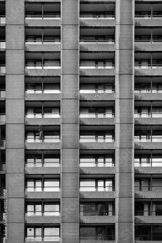 A close up of a block of flats with symmetrical grid pattern of windows and grey concrete walls