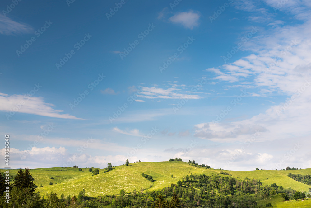 Green hilly landscape and blue sky during summer.