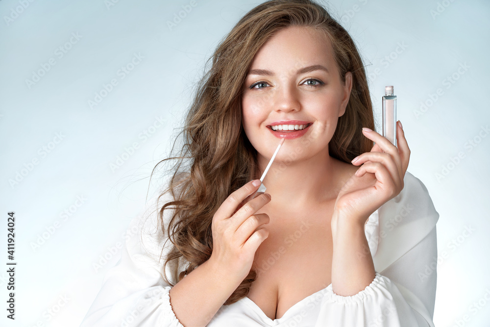 Woman with lip gloss. Photo of woman with perfect makeup on light blue background. Beauty and Skin care concept. Plus size model. Woman with lip gloss. Photo of woman with perfect makeup on light blue background. Beauty and Skin care concept. Plus size model.