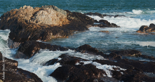 Sea waves splash against rock on island