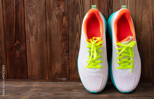 Pair of white sneakers on wooden background.