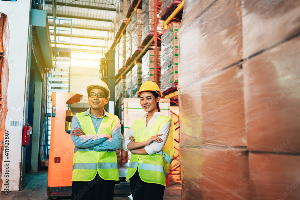 Obraz premium Working Team at warehouse. Manager man and asian woman warehouse worker standing with crossed arms to look at the camera.background driver at Warehouse forklift loader works with goods