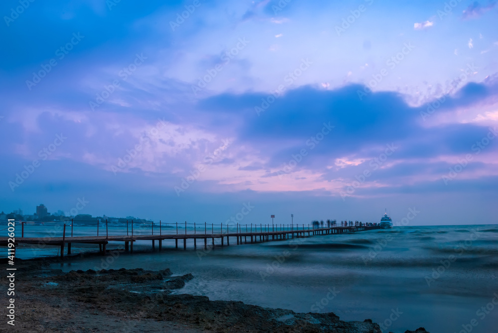Seascape. Pier against the backdrop of sunset sky with beautiful clouds and sea waves. Anapa. Krasnodar Territory.