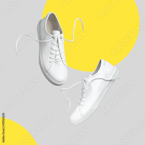 Flying white leather womens sneakers isolated on gray background. Trendy colors of the year 2021. Illuminating and Ultimate gray. Fashionable stylish sports casual shoes Creative minimalistic layout photo