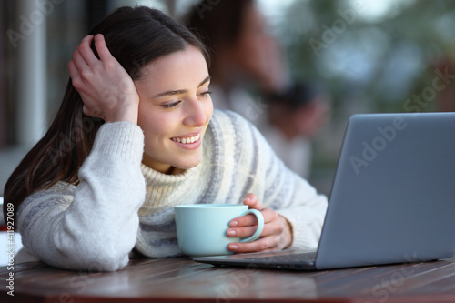 Happy woman watching media on laptop seated in a coffee shop