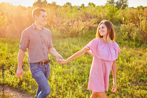 Shot of a young couple holding hands and running through the park.