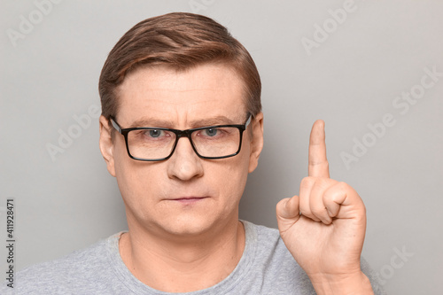 Portrait of serious focused mature man raising index finger