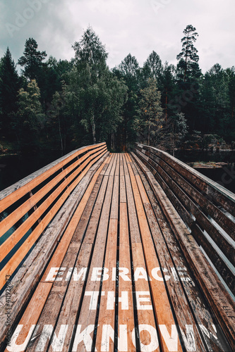 Fotografie, Obraz embrace the unknown text quote on wooden bridge towards the woods